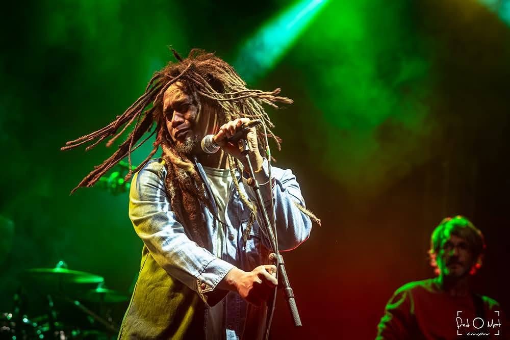 Le chanteur de Kingston Calling au micro sous des lumières vertes et rouges, tournée 2026