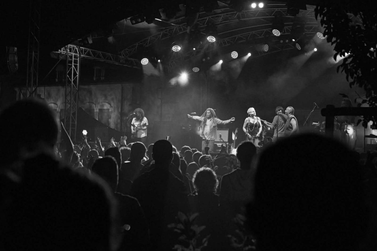Kingston Calling sur scène face au public, photo en noir et blanc, tournée 2026