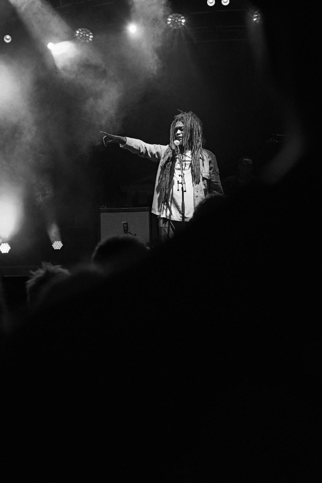 Le chanteur de Kingston Calling, bras tendu vers le public, photo en noir et blanc, tournée 2026